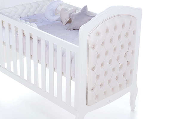 Cot with padded and upholstered headboard